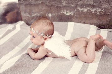 newborn baby girl with blue eyes a laurel wreath in her hair and angel winds