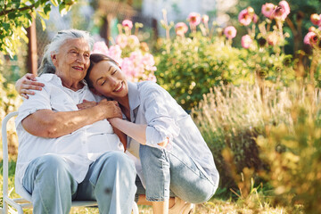 Time for a hugs. Young woman is with her senior mother is in the garden