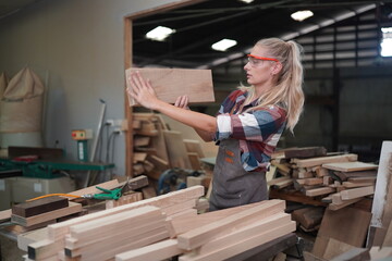 Fototapeta premium Contemporary Carpenter Working, Portrait of modern carpenter making wood furniture while working in joinery lit by sunlight with factory background on small business concept, copy space