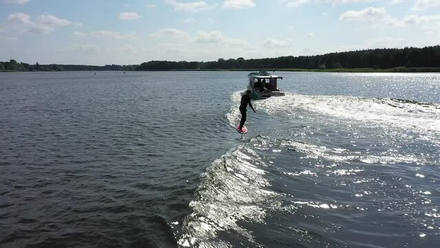 surfer on foil surfing waves behind boat