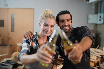 Happy Couple Carpenters have celeabate with a drink bottle after work of Assembling Furniture, Small business in wood DIY workplace office background