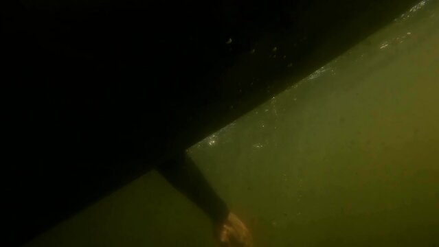 surfer on longboard is paddling filmed from under water