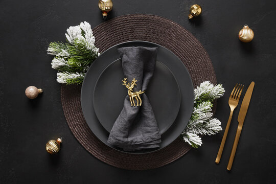 New Year black table setting with elegant golden decorations on black table for festive dinner and party. View from above.
