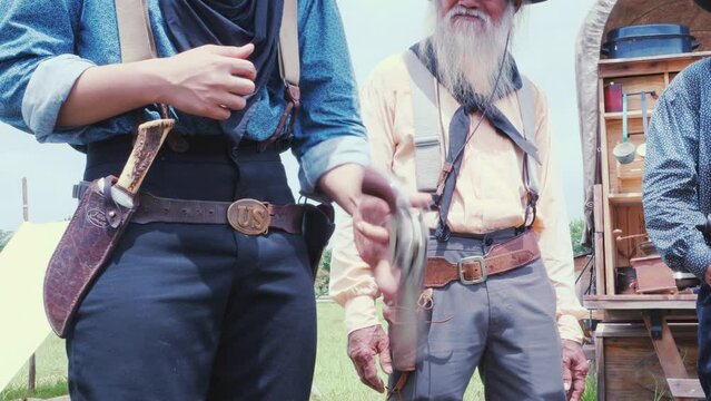 Slow motion of Man cowboy wielding  gun Carry and store into the gun holster at the waist in vintage cowboys village background. Cowboy 1800's Concept