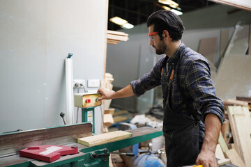 Contemporary Carpenter Working, Portrait of modern carpenter making wood furniture while working in joinery lit by sunlight with factory background on small business concept, copy space
