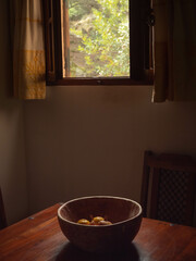 wooden bowl of fruit on an Italian kitchen table and open window 