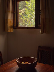interior of an Italian country house kitchen with an open window and bowl of fruit on the table 