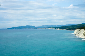 Aerial view of the azure sea framed by white cliffs with relict pines. A boat is rushing across the...