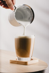 Cappuccino in a glass cup on a wooden table, Coffee and froth milk