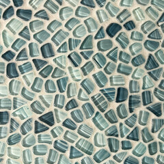 A tile wall in a bathroom in shades of blue that looks like sea glass