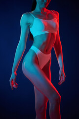 White underwear. Young woman is in the studio with neon lights