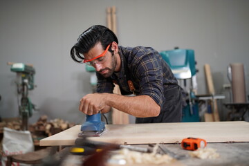 Contemporary Carpenter Working, Portrait of modern carpenter making wood furniture while working in joinery lit by sunlight with factory background on small business concept, copy space