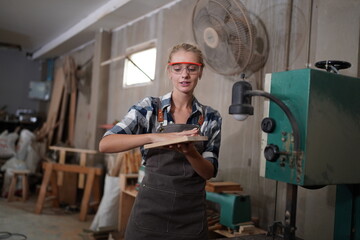 Contemporary Carpenter Working, Portrait of modern carpenter making wood furniture while working in joinery lit by sunlight with factory background on small business concept, copy space