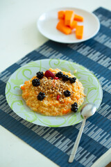 a cup of freshly brewed pumpkin porridge with berries on the table. healthy food idea