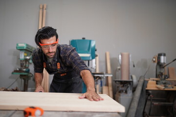 Contemporary Carpenter Working, Portrait of modern carpenter making wood furniture while working in joinery lit by sunlight with factory background on small business concept, copy space