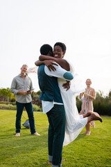 Naklejka na ściany i meble Happy african american couple with caucasian friends embracing during wedding