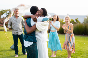 Happy african american couple embracing with caucasian friends during wedding