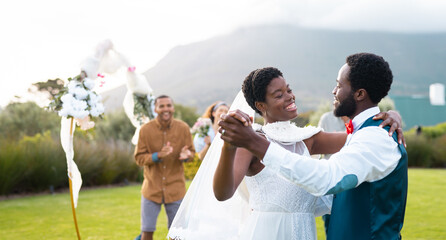 Happy african american couple holding hands and dancing during wedding