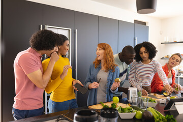 Happy diverse friends cooking together and smiling in kitchen