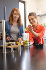 Happy diverse friends making healthy drink together in kitchen