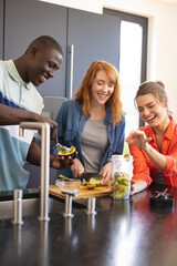 Happy diverse friends making healthy drink together in kitchen