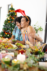 Happy diverse friends sitting at table and having dinner at christmas