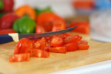 Cutting tomatoes for salad. Hand cut tomatoes on wood board. Selective focus