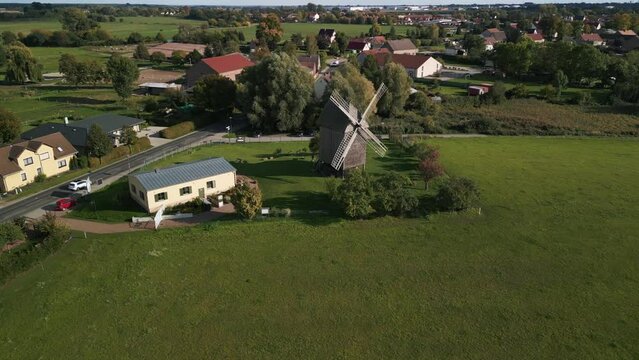 Deep sun long shadows. Dramatic aerial view flight fly push in drone
of a old Wooden Trestle windmill in brandenburg Germany at summer golden hour 2022. 4k marnitz Cinematic