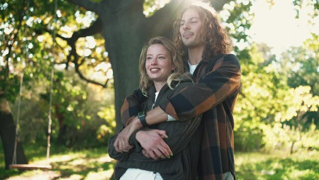 Pretty young couple hugging and talking in the park outdoors