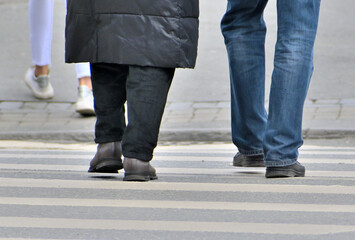 Fototapeta premium A man and a woman walk along the zebra crossing on an autumn day