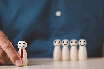 A businessman's hand selects a wooden figure that stands out from the crowd. leadership concept conflict in the organization inconsistency Selection of personnel. Wooden puppet. Wooden doll. - obrazy, fototapety, plakaty