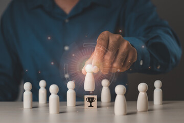 A businessman's hand selects a wooden figure that stands out from the crowd. Human resource management concepts, leadership, teamwork, recruiting, business and finance, wooden puppets, wooden blocks.