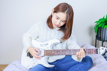室内でギターを弾く女性、趣味、習い事、芸能人