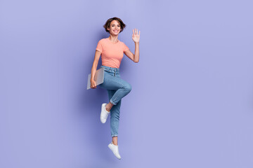 Full length photo of shiny friendly lady wear striped t-shirt jumping holding modern device waving arm empty space isolated violet color background