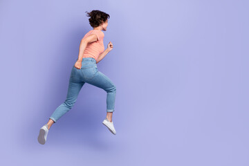 Full length photo of pretty hurrying lady wear striped t-shirt running fast jumping high empty space isolated violet color background