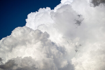 Large white cumulus thunderclouds against a blue sky before rain
