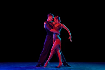 Foto auf Acrylglas Stylish ballroom dancers couple in gorgeous outfits dancing in sensual pose on dark background in neon light. Concept of art, music, dance, emotions. © master1305