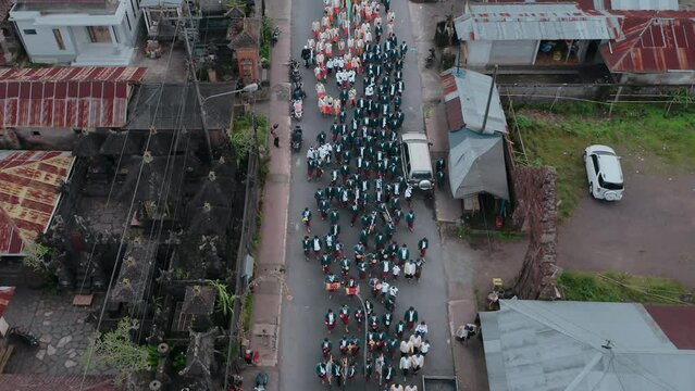 Top view of hindu ceremony parade making a traffic jam in street. Aerial view of procession of Indonesian Balinese people wearing national costumes. Aerial landscape view of city with religion parade.