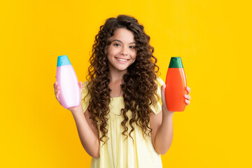 Happy teenager, portrait of child girl with bottle shampoo conditioners or shower gel. Kids hair care. Hair cosmetic product, shampoo bottle. Smiling girl.