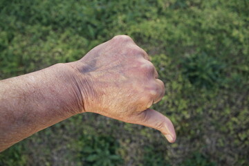 La mano del hombre con el pulgar hacia abajo tiene el significado de todo lo negativo, formando un diseño de postura de gesto original con un fondo de la hierba verde - obrazy, fototapety, plakaty