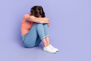 Full size photo of lovely young girl sit floor cuddle knees crying wear trendy striped garment isolated on violet color background