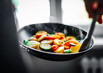 Woman cooking tasty vegetable mix stew in pan on kitchen
