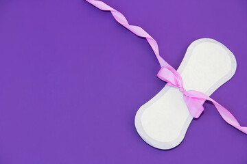 white women's hygienic daily pad and pink bow on a purple background