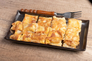 Crispy roti topped with milk in a black plate
