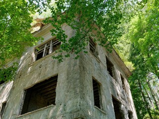 Low-angle shot of an abandoned sanatorium surrounded by trees - obrazy, fototapety, plakaty