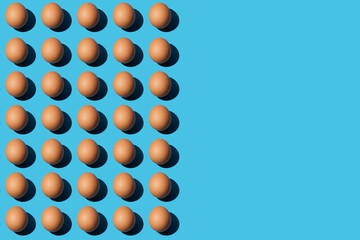 Trendy pattern of brown chicken eggs on the left half of the blue background. Right side for copy...