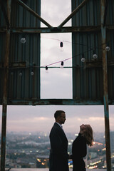Romantic, young and happy caucasian couple in stylish clothes on the rooftop enjoying view and time together. Art portrait of beautiful woman and man. Love, relationships, romance, happiness concept.