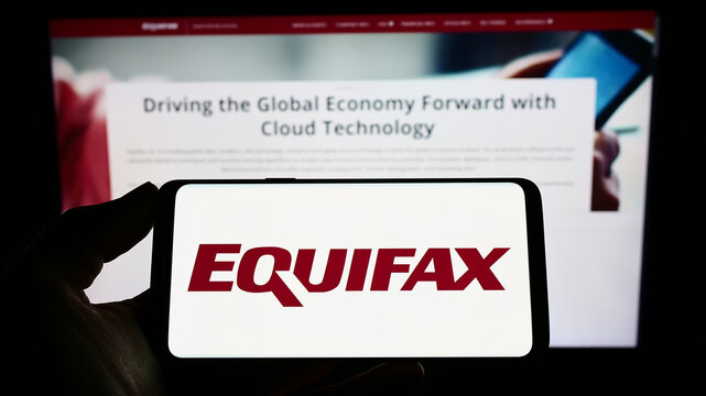 Stuttgart, Germany - 10-01-2022: Person holding smartphone with logo of US consumer credit reporting company Equifax Inc. on screen in front of website. Focus on phone display.