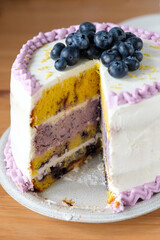 Blueberry lemon birthday or wedding cake with a slice cut out. - 537545846