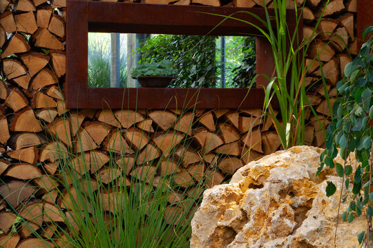 Im Gras Brennholz Stapel mit Fenster vor einem Naturstein 